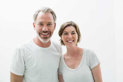 Implantologie RUE104: Sanft, sicher und bezahlbar! Proträtfoto von einem Mann und einer Frau mit Implantaten