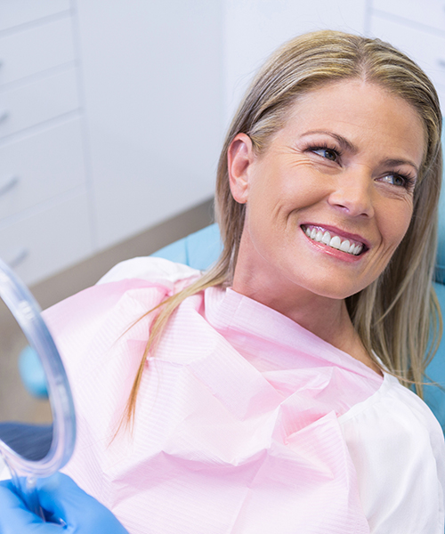 lächelnde Frau sitzt auf einen Behandlungsstuhl bei einem Zaharzt